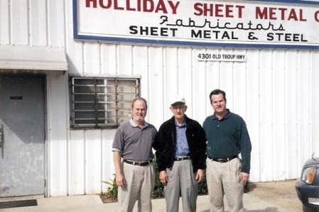 Three men standing in front of a building.