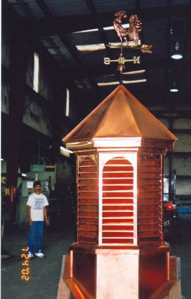 A man standing next to a building with a copper roof.