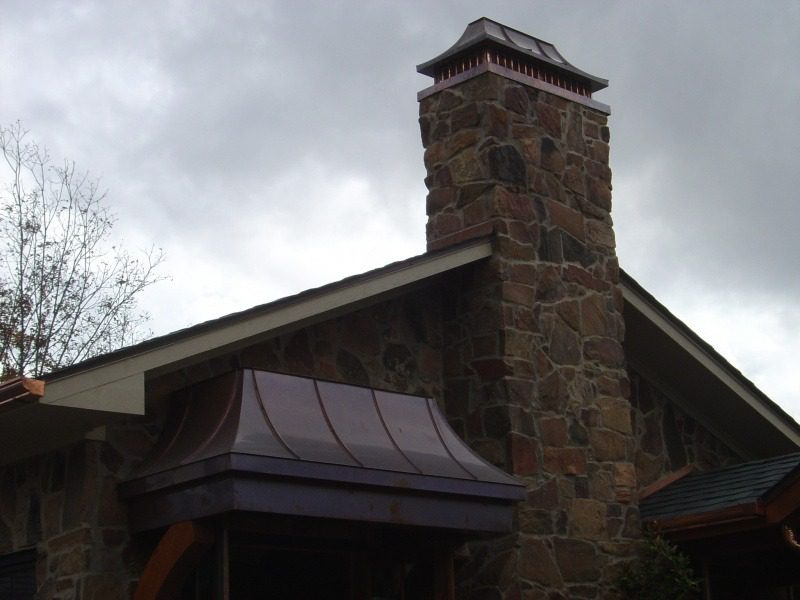 A building with a large stone chimney and roof.