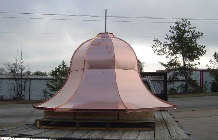 A large copper bell sitting on top of a wooden platform.